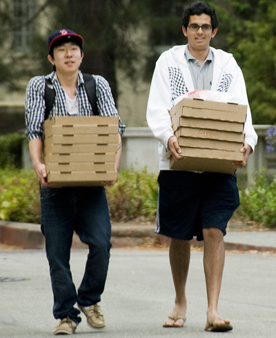Guys carrying pizzas